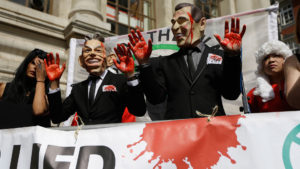 Protesters wearing a former British Prime Minister Tony Blair mask, left, and former U.S. President George W. Bush mask pose for the media outside the Queen Elizabeth II Conference Centre in London, shortly before the publication of the Chilcot report into the Iraq war, Wednesday, July 6, 2016. The long awaited British inquiry into the 2003 invasion of Iraq has been published. Led by former senior civil servant John Chilcot, the report took over seven years to prepare and runs over two million words. The report did not analyze the legality of the invasion and instead focused on the British decision-making process in the run up to the war in 2003. (AP Photo/Matt Dunham)